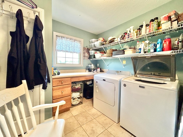 laundry room featuring light tile patterned flooring, a textured ceiling, and washing machine and clothes dryer