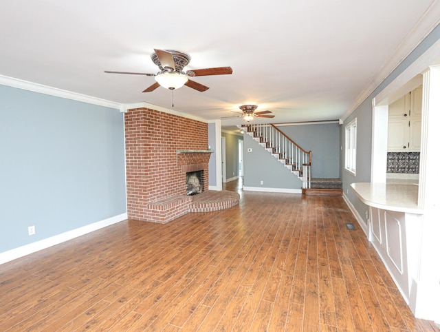 unfurnished living room with light hardwood / wood-style floors, ornamental molding, ceiling fan, and a brick fireplace