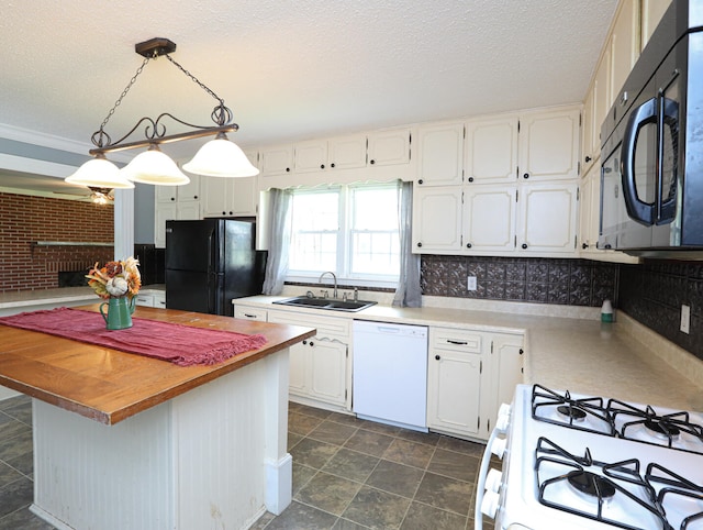 kitchen with sink, white appliances, dark tile patterned floors, white cabinetry, and pendant lighting