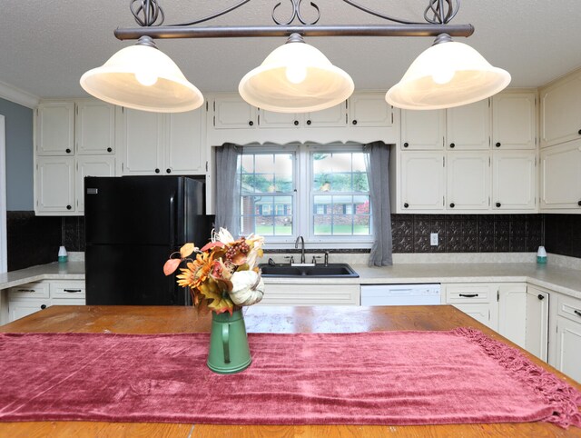 kitchen featuring sink, tasteful backsplash, black refrigerator, and pendant lighting