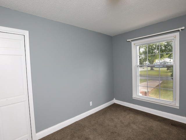 unfurnished room with dark carpet and a textured ceiling