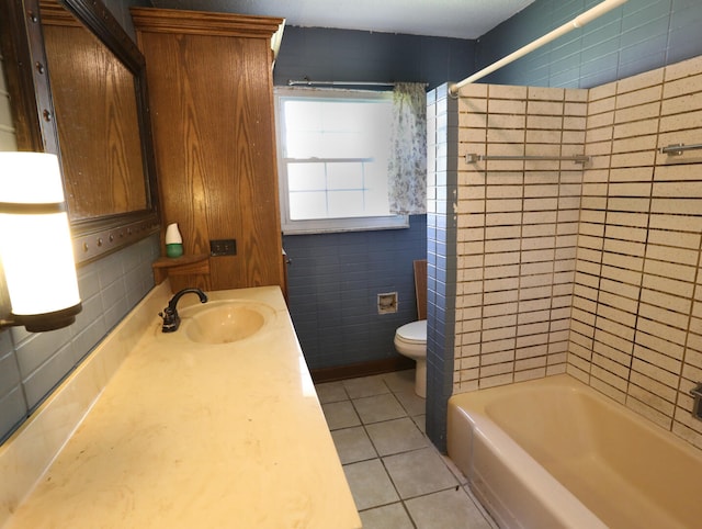 full bathroom featuring toilet, vanity, tile walls, tile patterned floors, and tiled shower / bath combo