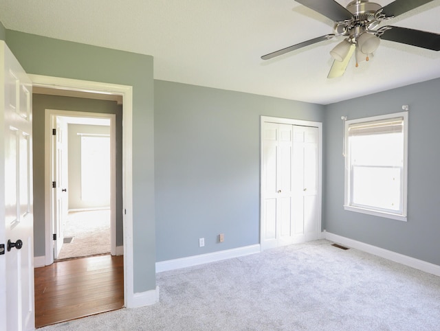 unfurnished bedroom with ceiling fan, carpet, and a closet