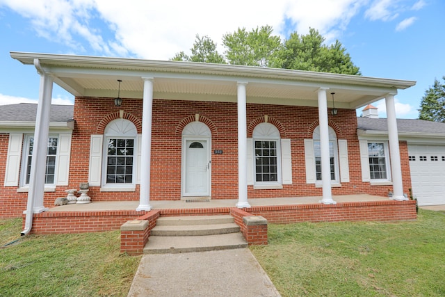 view of front facade with a garage, a front lawn, and covered porch