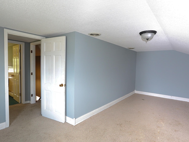 bonus room with a textured ceiling, lofted ceiling, and light colored carpet