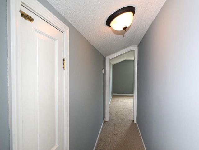 corridor featuring carpet flooring, a textured ceiling, and lofted ceiling