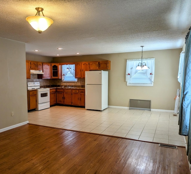 kitchen featuring pendant lighting, light wood-type flooring, a healthy amount of sunlight, and white appliances