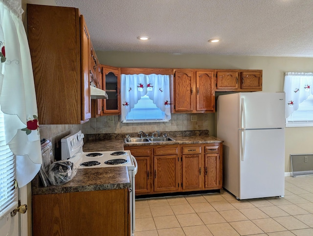 kitchen featuring tasteful backsplash, a textured ceiling, light tile patterned floors, sink, and white appliances