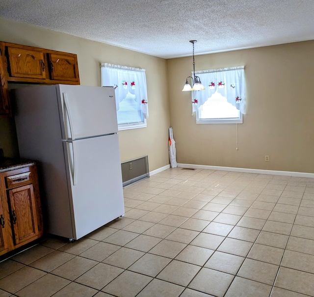 kitchen with light tile patterned flooring, white fridge, decorative light fixtures, a notable chandelier, and a textured ceiling