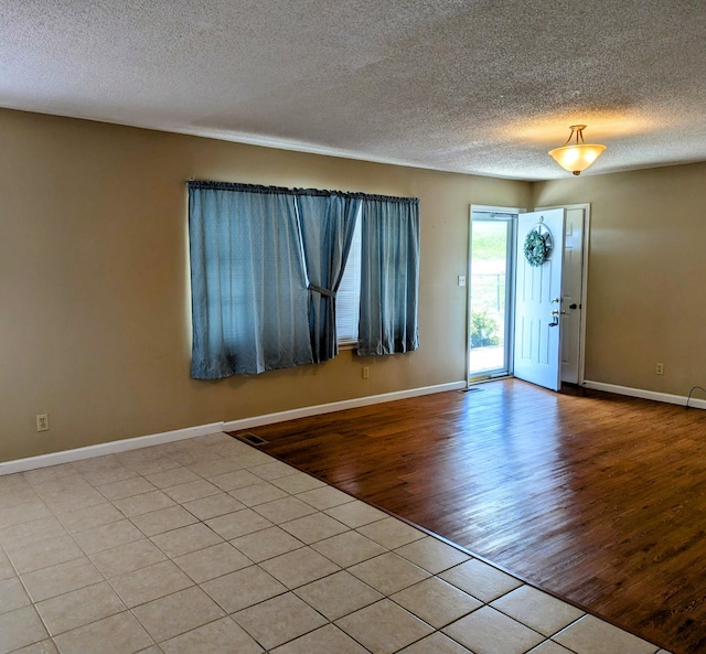 empty room featuring a textured ceiling and light hardwood / wood-style flooring