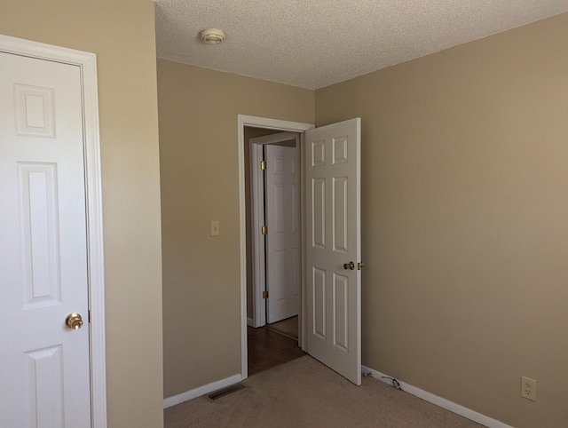 unfurnished bedroom with a textured ceiling and light carpet