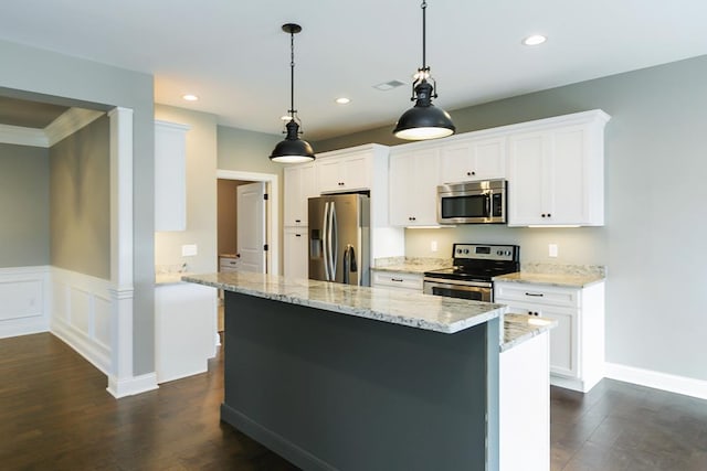 kitchen with dark hardwood / wood-style floors, hanging light fixtures, white cabinetry, light stone countertops, and stainless steel appliances