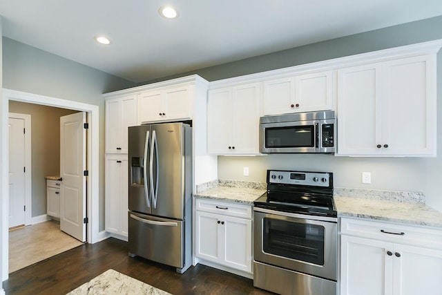 kitchen with white cabinetry, dark hardwood / wood-style floors, stainless steel appliances, and light stone countertops