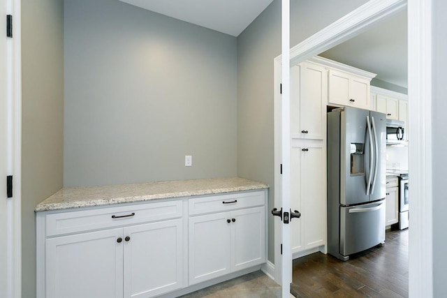 kitchen featuring appliances with stainless steel finishes, light stone counters, white cabinets, and dark hardwood / wood-style flooring