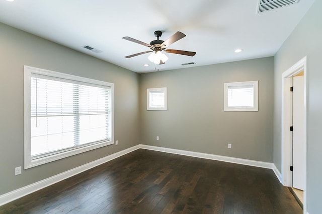 empty room with ceiling fan, plenty of natural light, and dark hardwood / wood-style flooring