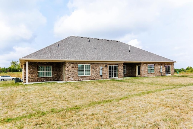 back of house with central AC unit and a yard