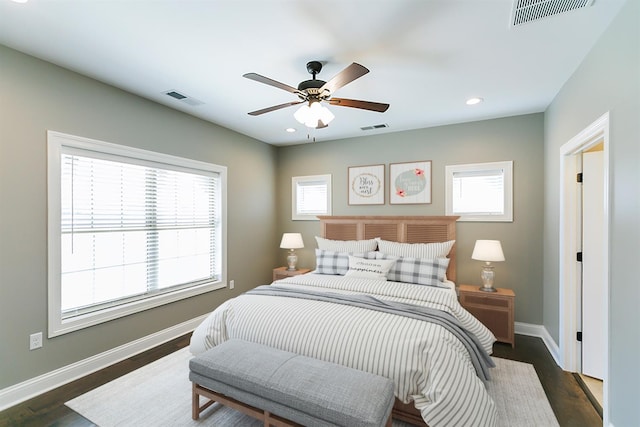 bedroom featuring ceiling fan, dark wood-type flooring, and multiple windows