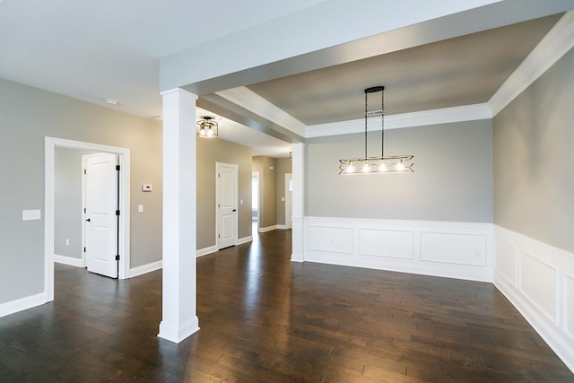 spare room featuring decorative columns, crown molding, and dark wood-type flooring