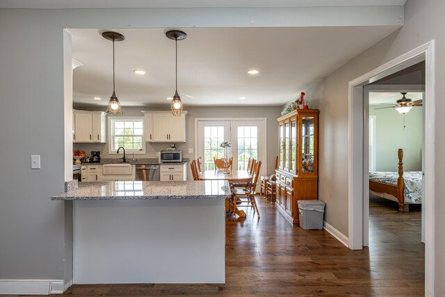 kitchen with ceiling fan, dark hardwood / wood-style flooring, white cabinetry, appliances with stainless steel finishes, and decorative light fixtures