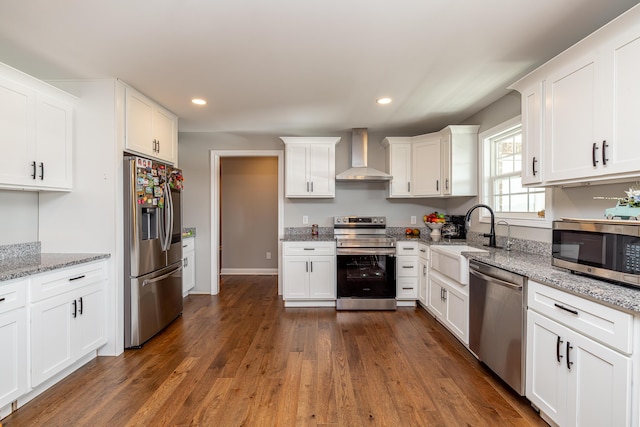 kitchen featuring dark wood-style flooring, a sink, white cabinetry, appliances with stainless steel finishes, and wall chimney exhaust hood