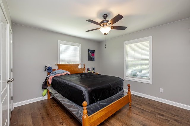 bedroom with a ceiling fan, multiple windows, baseboards, and wood finished floors