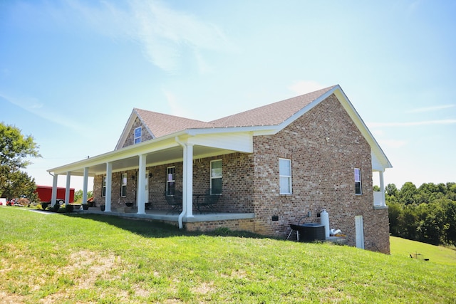 rear view of property featuring brick siding, central AC, and a yard