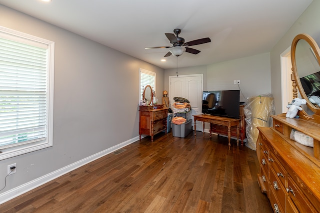 living room featuring a wealth of natural light, ceiling fan, and dark wood-type flooring