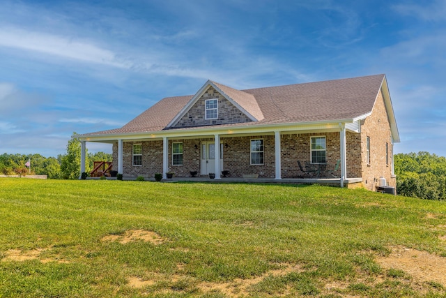 view of front of property featuring covered porch, brick siding, central AC, and a front yard