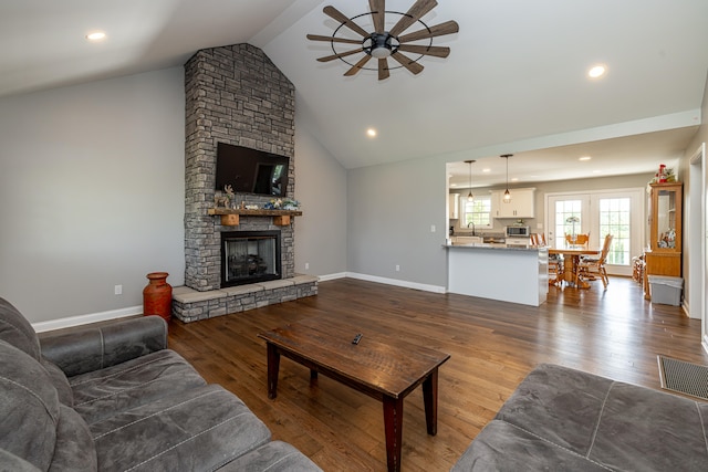 living room featuring hardwood / wood-style flooring, ceiling fan, sink, and a stone fireplace