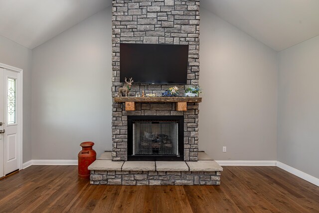 living room featuring hardwood / wood-style floors, vaulted ceiling, brick wall, and a fireplace