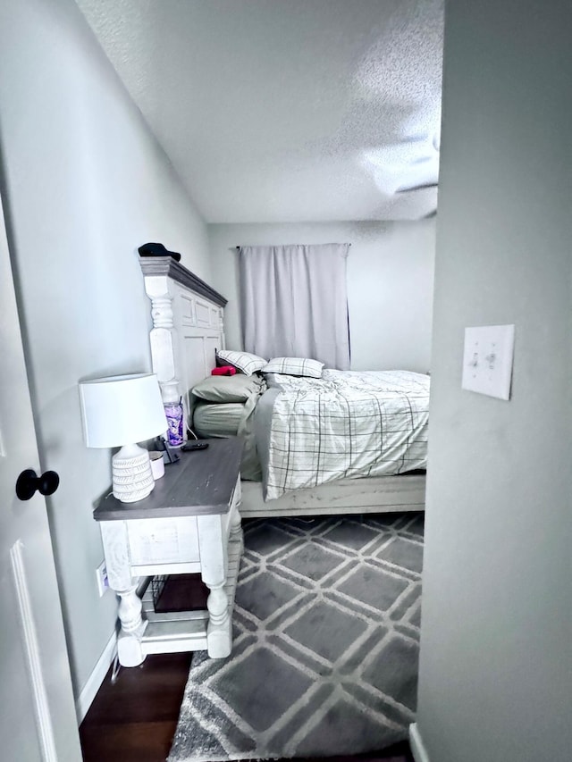 bedroom featuring a textured ceiling and dark hardwood / wood-style flooring