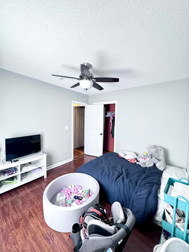 bedroom featuring a textured ceiling, a closet, ceiling fan, and dark hardwood / wood-style flooring