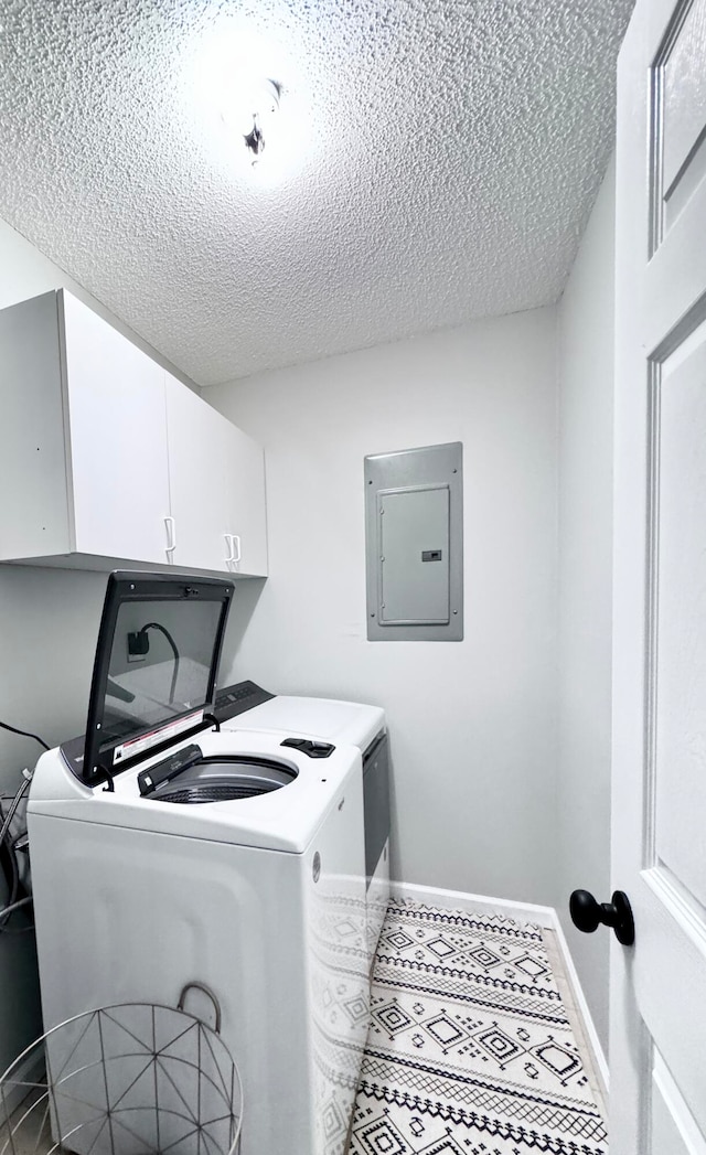 clothes washing area with tile patterned floors, cabinets, a textured ceiling, electric panel, and washer and dryer