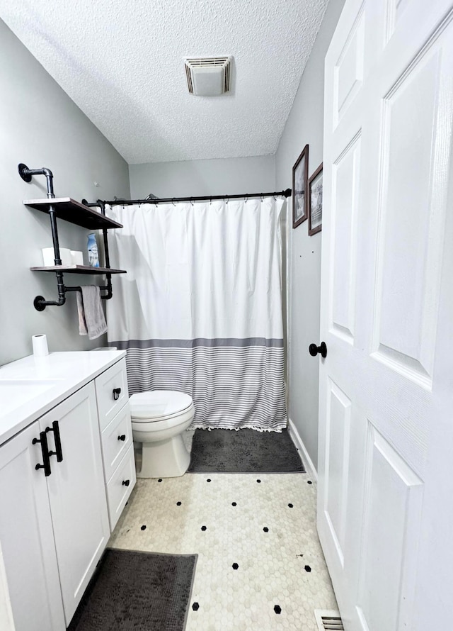 bathroom with tile patterned floors, a textured ceiling, vanity, and toilet