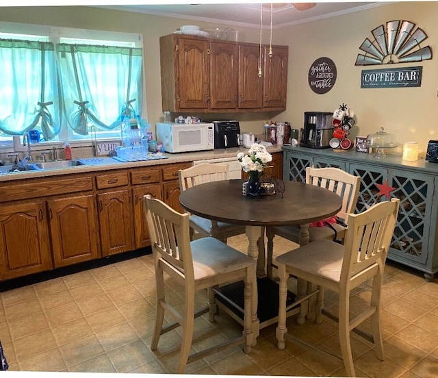 kitchen with crown molding, sink, and light tile patterned flooring