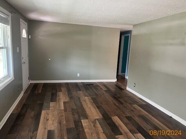 unfurnished room with a textured ceiling and dark wood-type flooring