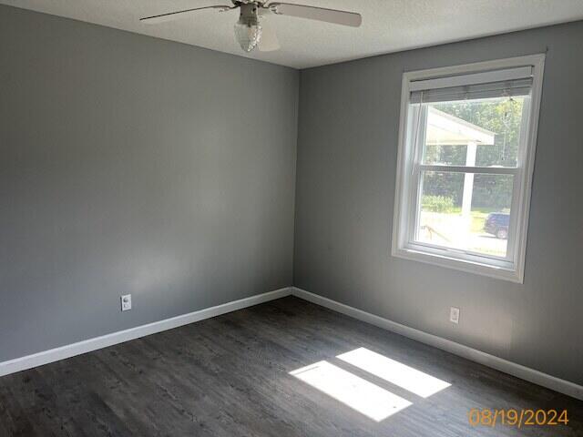 spare room featuring ceiling fan, dark hardwood / wood-style floors, and a textured ceiling