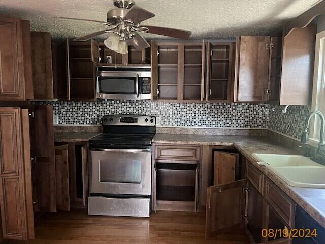 kitchen with appliances with stainless steel finishes, dark hardwood / wood-style floors, tasteful backsplash, sink, and ceiling fan