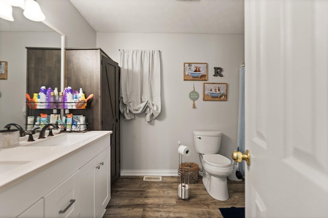 bathroom with wood-type flooring, toilet, and vanity