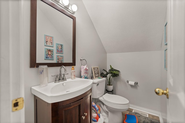 bathroom with toilet, vanity, and lofted ceiling