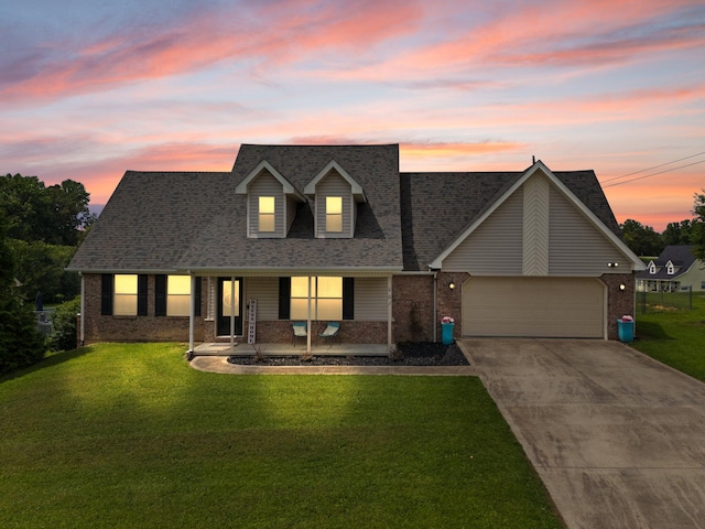 cape cod house featuring a garage and a lawn