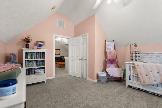 carpeted bedroom featuring ceiling fan, a crib, and lofted ceiling