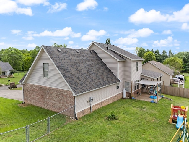 rear view of property featuring a playground, a patio area, and a yard