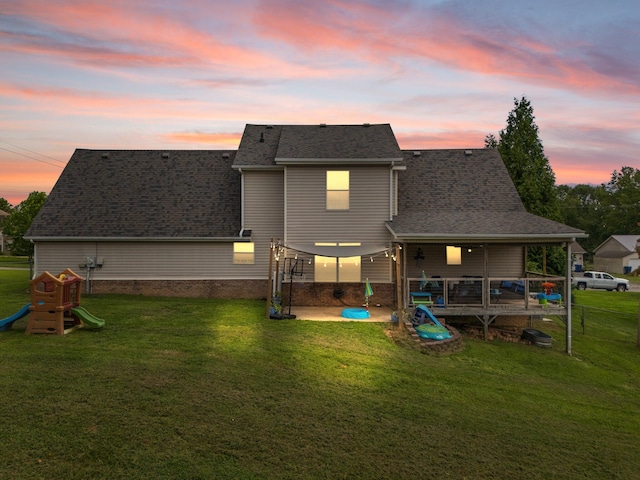 back house at dusk featuring a lawn