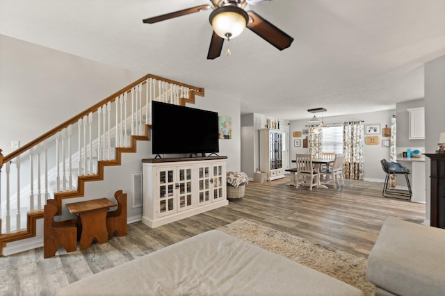 living room with ceiling fan with notable chandelier and hardwood / wood-style flooring