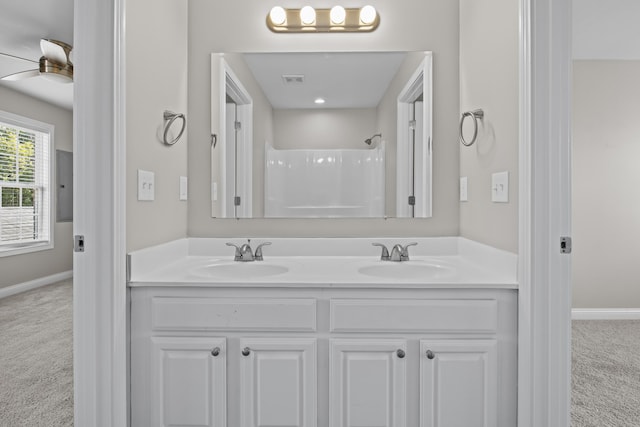 bathroom with double vanity, walk in shower, a sink, and baseboards