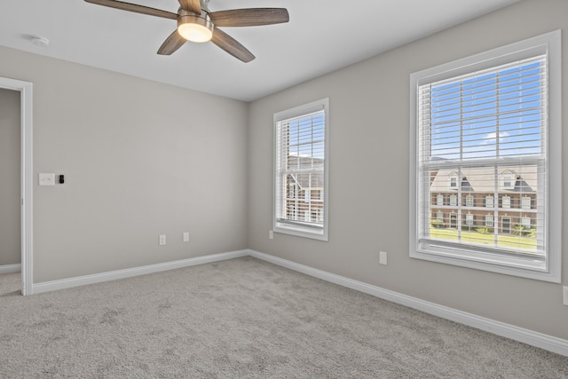 carpeted empty room with a ceiling fan and baseboards