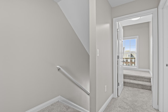 hallway featuring carpet flooring, an upstairs landing, and baseboards