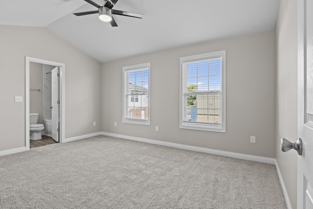 unfurnished bedroom with lofted ceiling, carpet floors, ensuite bathroom, and baseboards