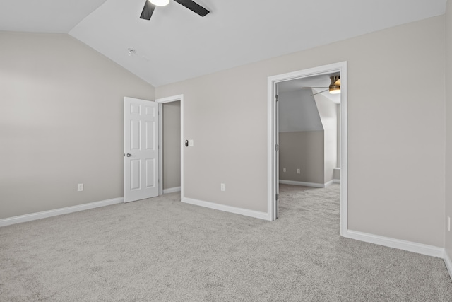 unfurnished bedroom with ceiling fan, carpet floors, baseboards, vaulted ceiling, and a walk in closet